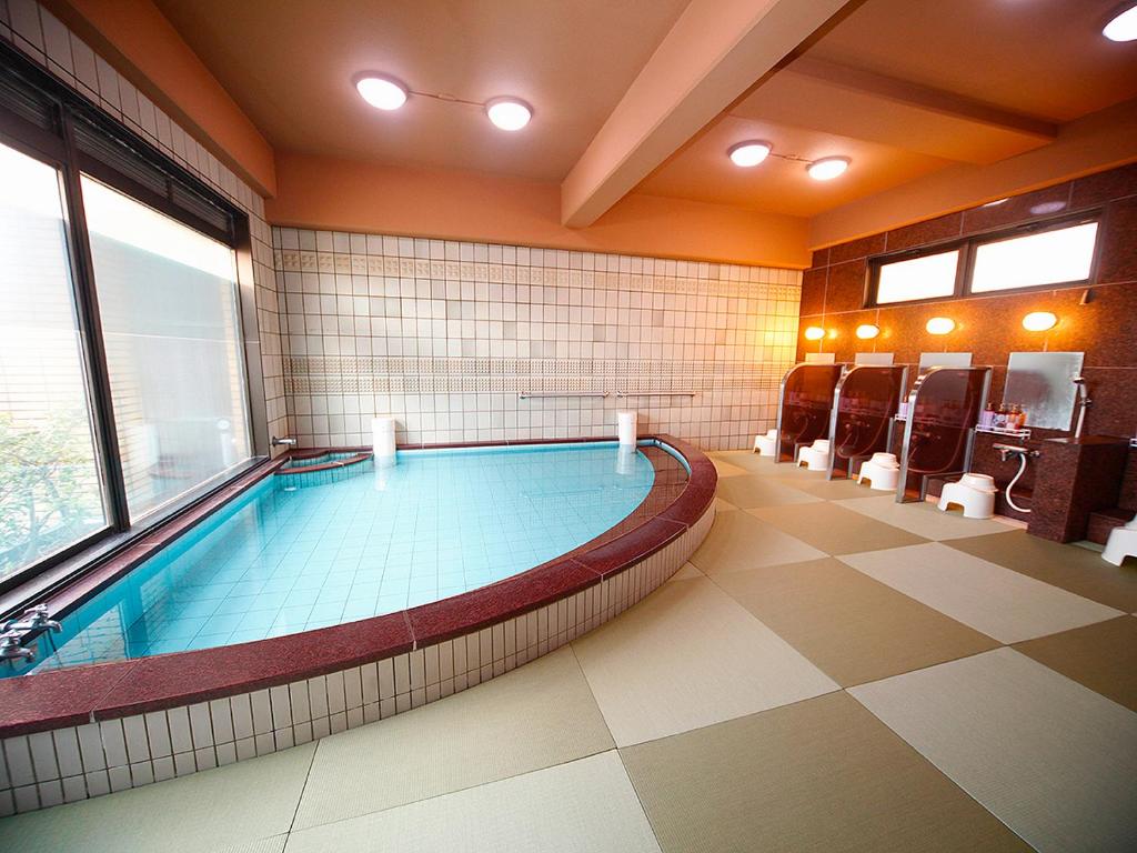 a large swimming pool in a room with a large window at Hotel Takasago in Kochi