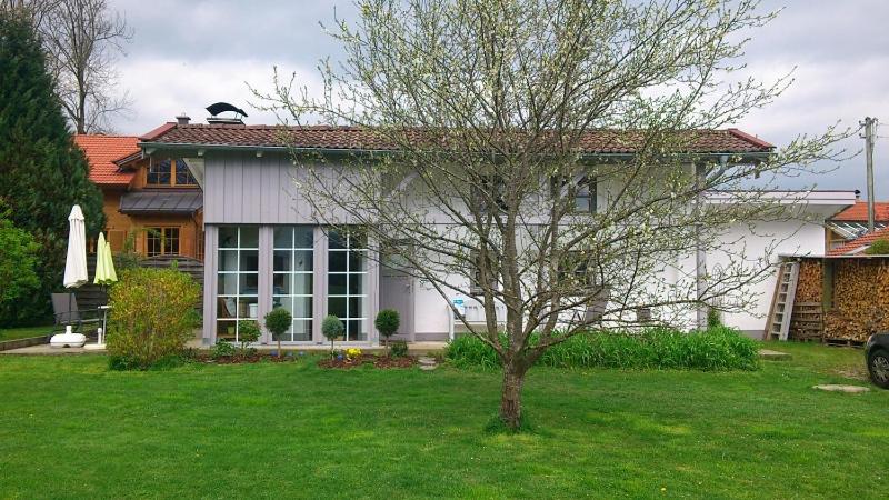 ein kleines weißes Haus mit einem Baum im Hof in der Unterkunft Ferienhaus Schmidt in Bernau am Chiemsee