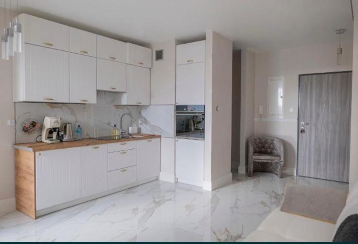 a white kitchen with white cabinets and a chair at Apartment Kaczorowskiego 14 in Białystok