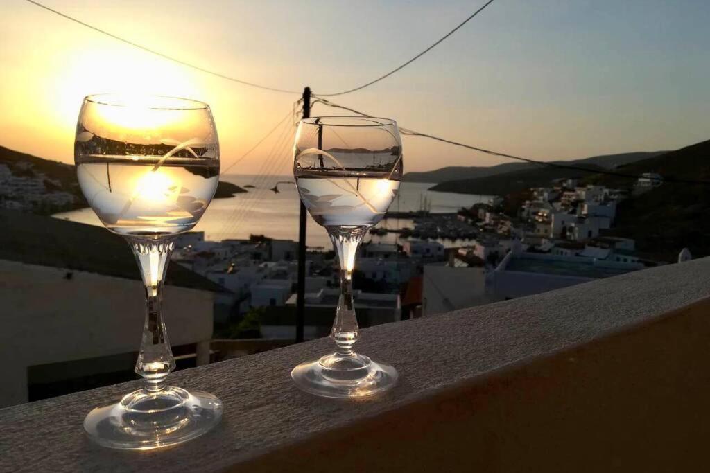 two wine glasses sitting on a ledge with the sunset at Villa Christina in Kithnos