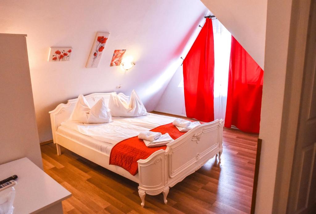 a bedroom with a white bed with red curtains at Pensiunea Vila Silva I in Haţeg