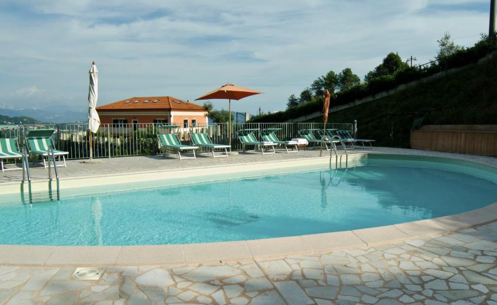 a large swimming pool with chairs and an umbrella at Olivium in La Spezia