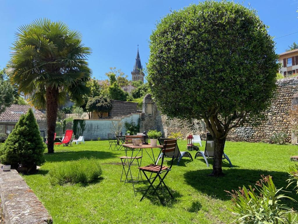 einen Garten mit einem Tisch, Stühlen und einem Baum in der Unterkunft Le Charles IX in Roussillon en Isere