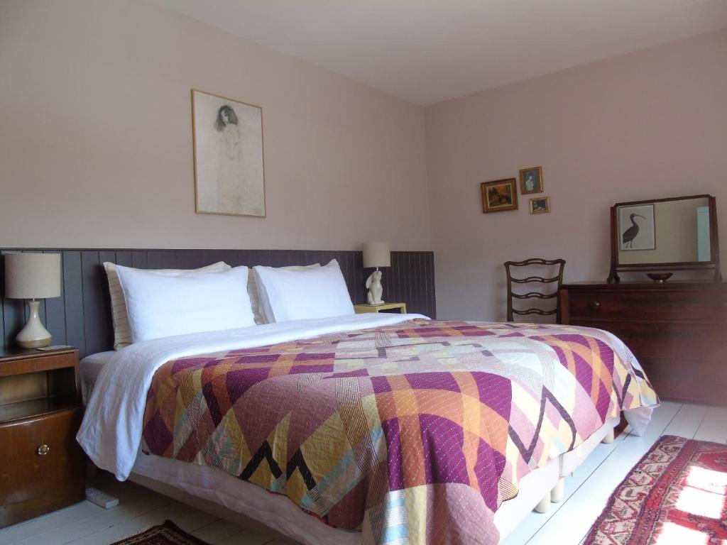 a bedroom with a large bed with a colorful blanket at Rowan Cottage, CrannachCottages in Garve
