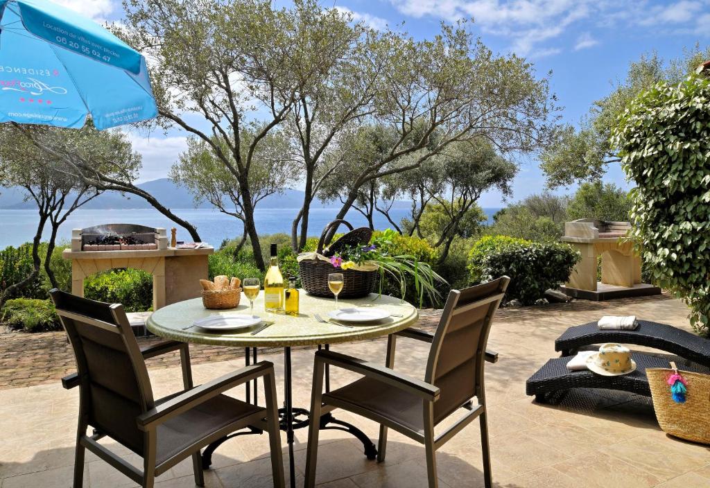 um pátio com uma mesa, cadeiras e um guarda-sol em Résidence Arco Plage em Olmeto