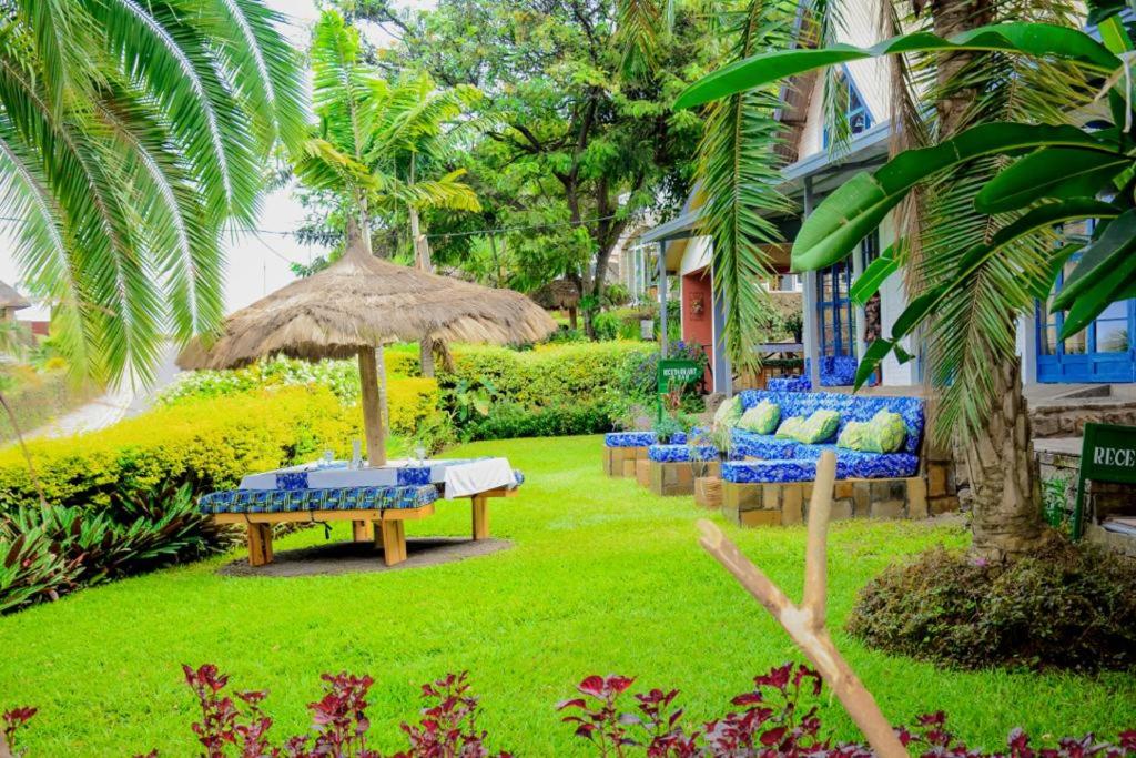 a yard with chairs and a table and an umbrella at Palm Garden Resort in Gisenyi