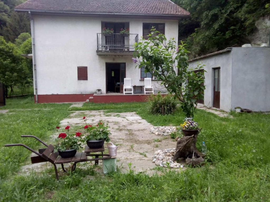 a white house with a table and flowers in front of it at Šumska idila Rakovac in Zmajevac