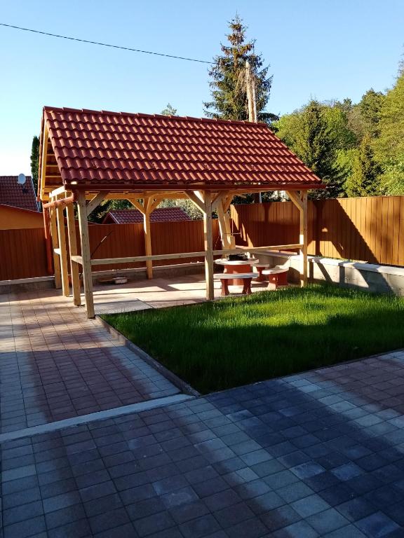 a wooden pavilion with a picnic table in a yard at Country Vendégház in Szilvásvárad