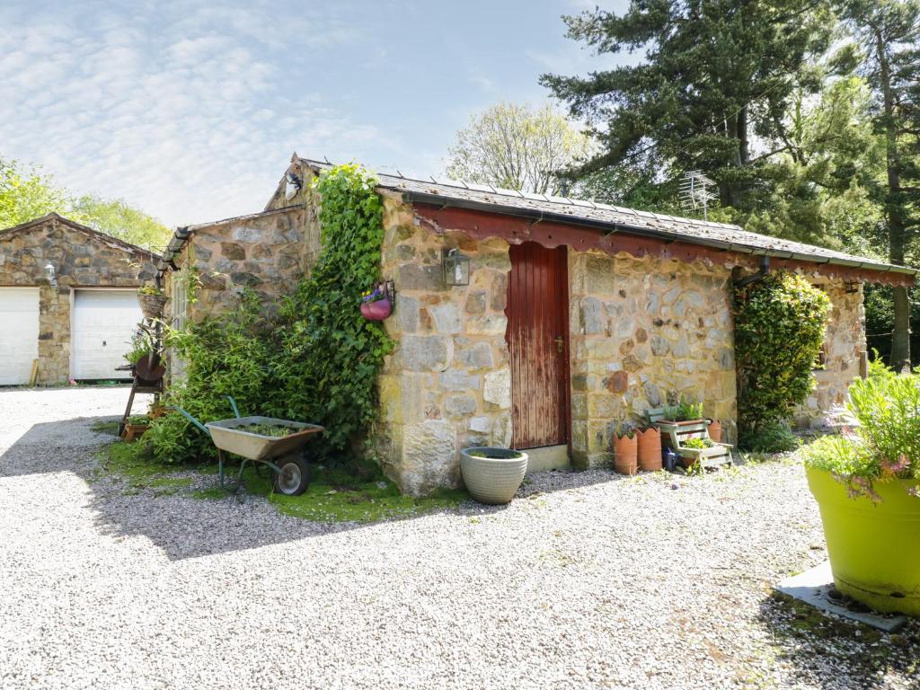 a stone house with a red door and a yard at Redwood Lodge in Wrexham