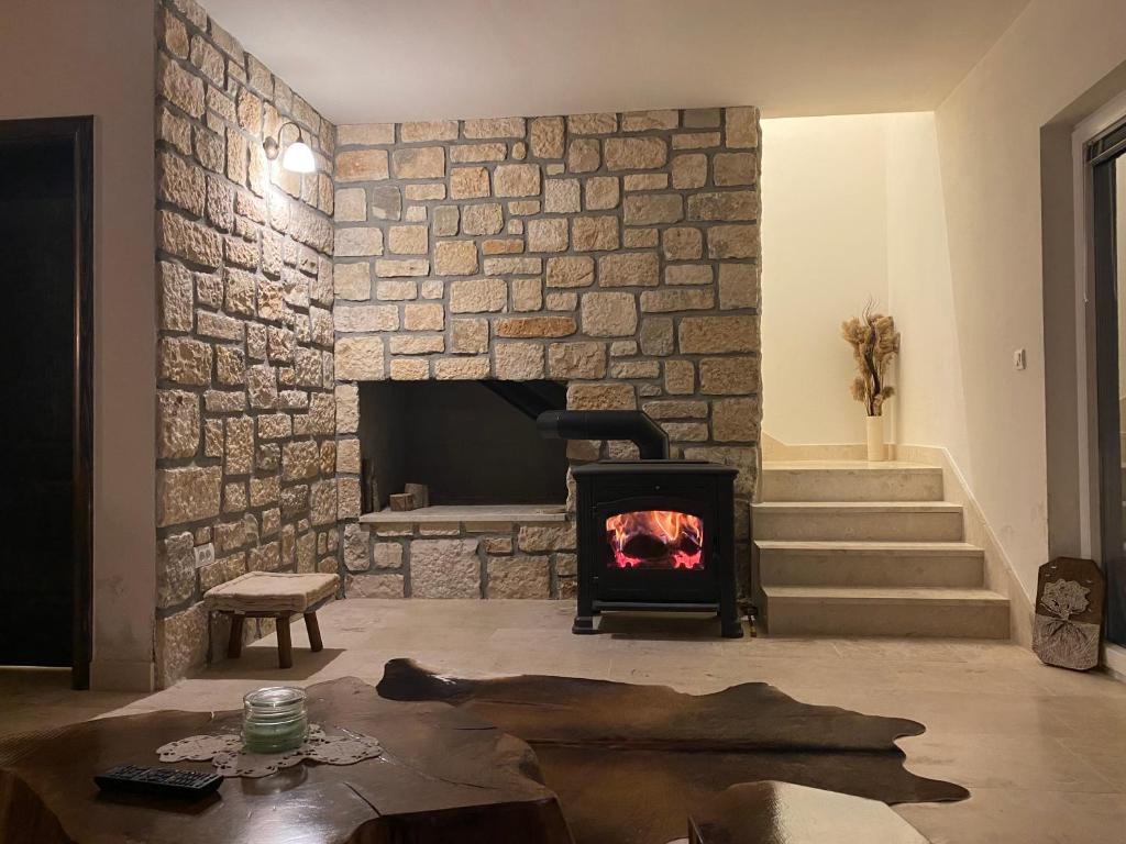 a living room with a stone wall with a fireplace at Milka house in Korenica