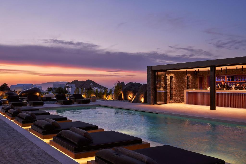 a pool with chaise lounge chairs next to a building at SantAnna Luxury Suites in Imerovigli