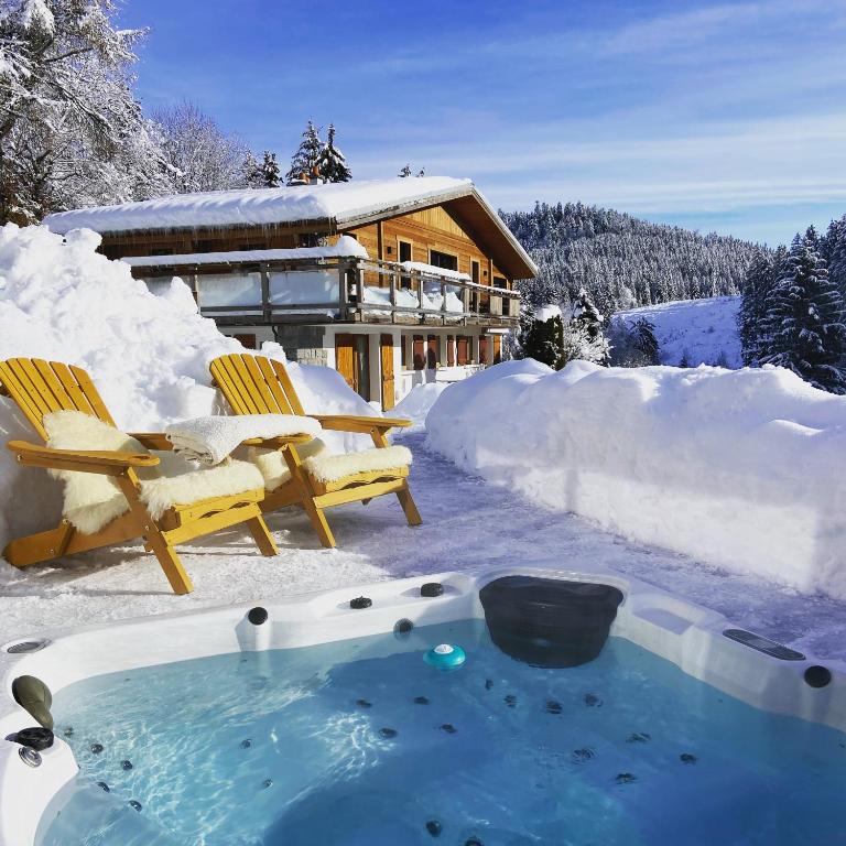 un bain à remous dans la neige devant une maison dans l'établissement Appartement de montagne au Chalet de Snow, à Xonrupt-Longemer