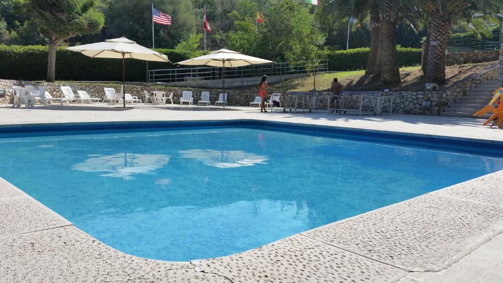 ein großer blauer Pool mit Stühlen und Sonnenschirmen in der Unterkunft Residence Napoleon by HelloElba in Procchio