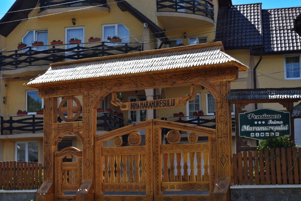 a wooden gazebo in front of a building at Pensiunea Inima Maramureșului in Breb