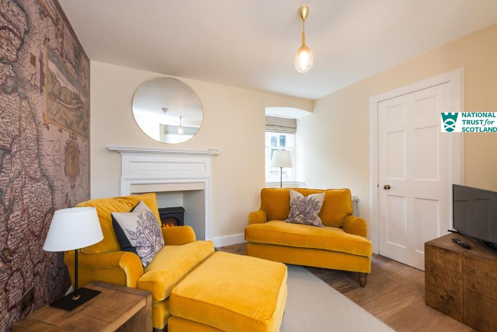 a living room with a yellow couch and a tv at The Riddoch Apartment by The National Trust Scotland in Edinburgh