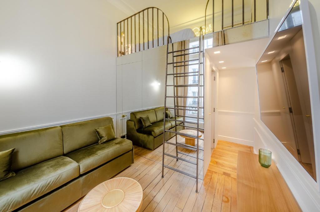 a living room with a green couch and a ladder at Appartement de standing 1 – tour Eiffel/Invalides in Paris