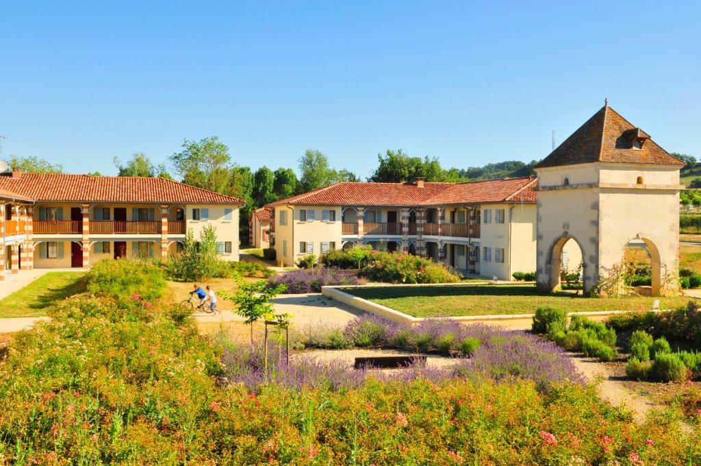 un jardin en face d'un bâtiment fleuri dans l'établissement Résidence Goélia Aquaresort, à Nérac