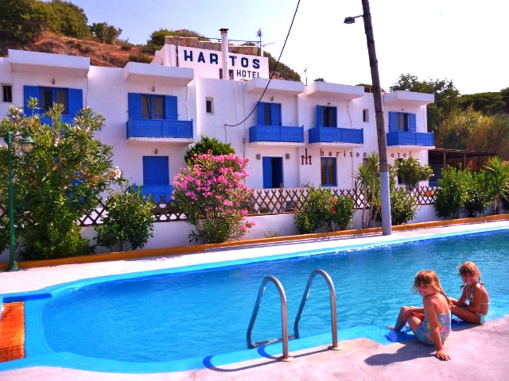 two children sitting in a swimming pool in front of a hotel at Haritos Hotel - Geothermal Hot Swimming Pool in Mandrákion