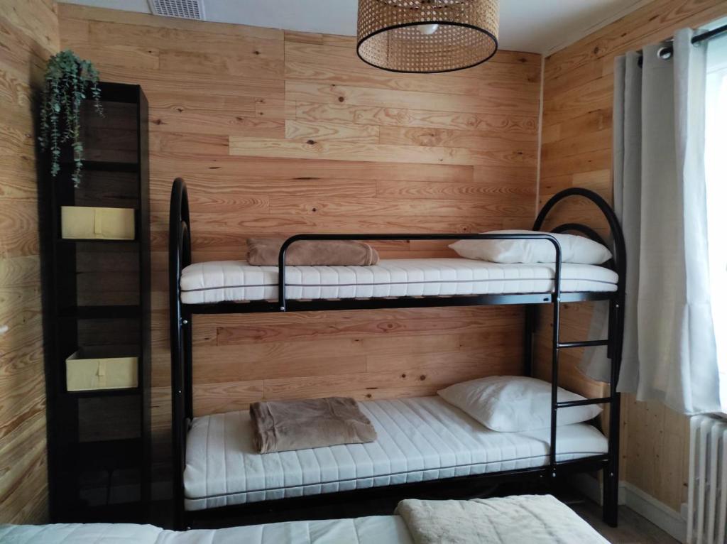 2 literas en una habitación con pared de madera en L'escapade, en La Bourboule