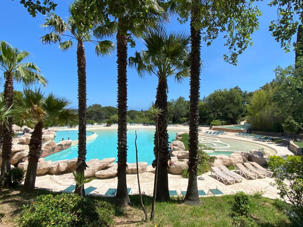 a swimming pool with palm trees in a resort at Domaine des Restanques, suite parentale ,vue mer. in Grimaud