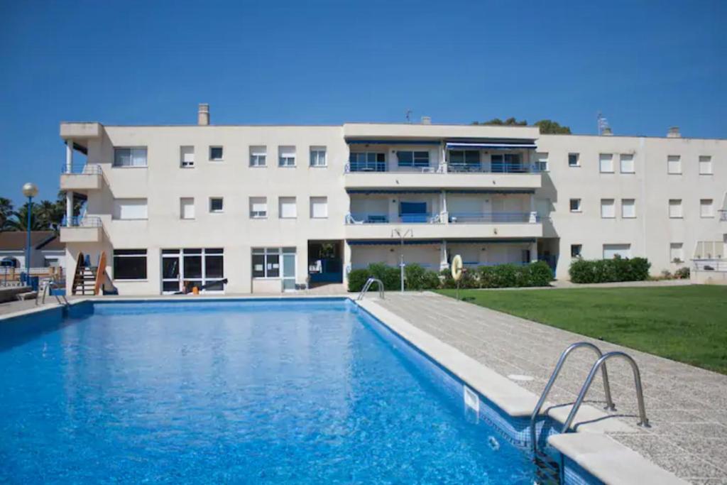a swimming pool in front of a large building at Apartamento Eucaliptus B - Delta del Ebro in L'Eucaliptus