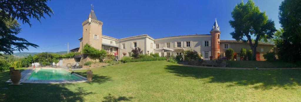 a large house with a swimming pool in the yard at Chateau des Janroux in Juliénas