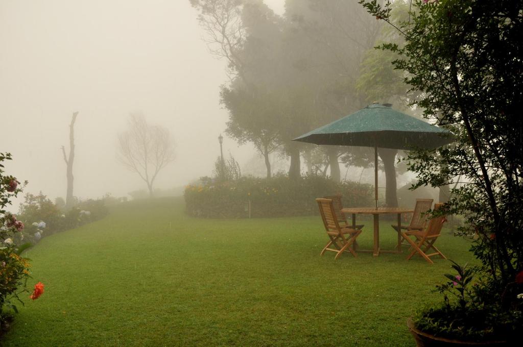 un tavolo e sedie con ombrellone in un cortile di Clouds Holiday Bungalow Haputhale a Haputale