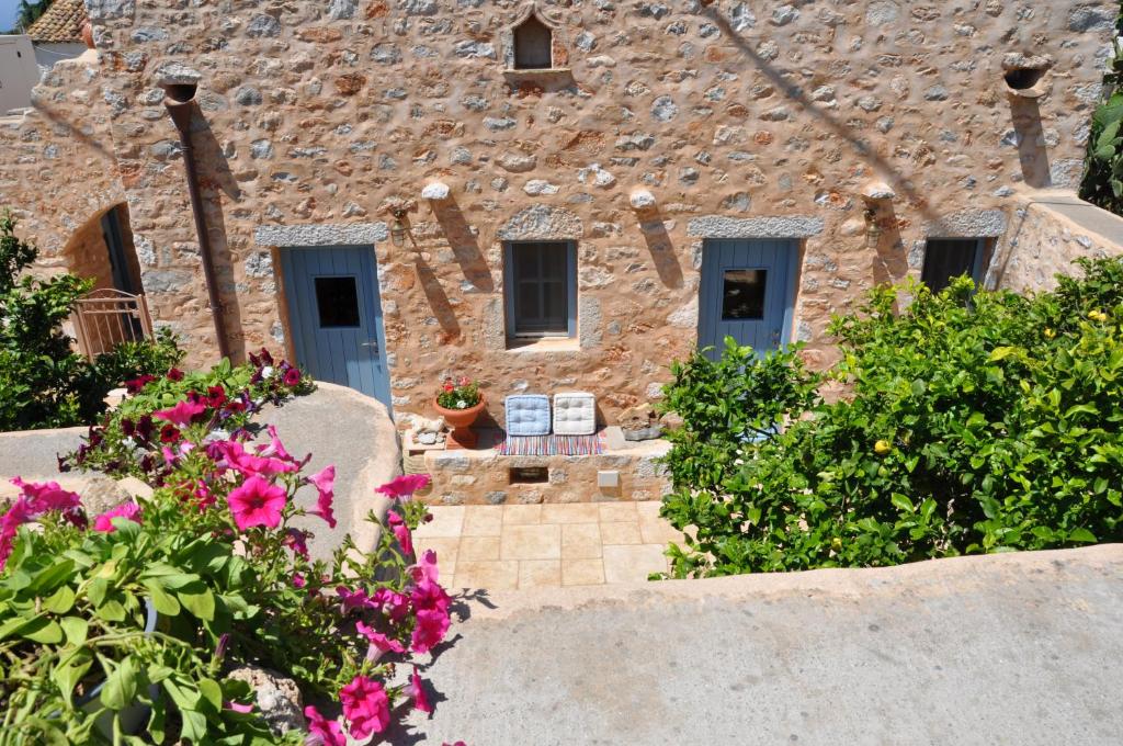 une maison en pierre avec des fleurs devant elle dans l'établissement Petrounis Hotel, à Areópoli