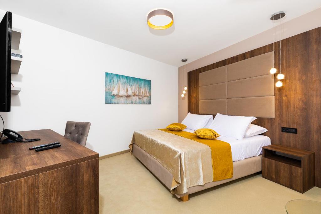 a bedroom with a bed and a desk and a television at Hotel Meduza in Senj