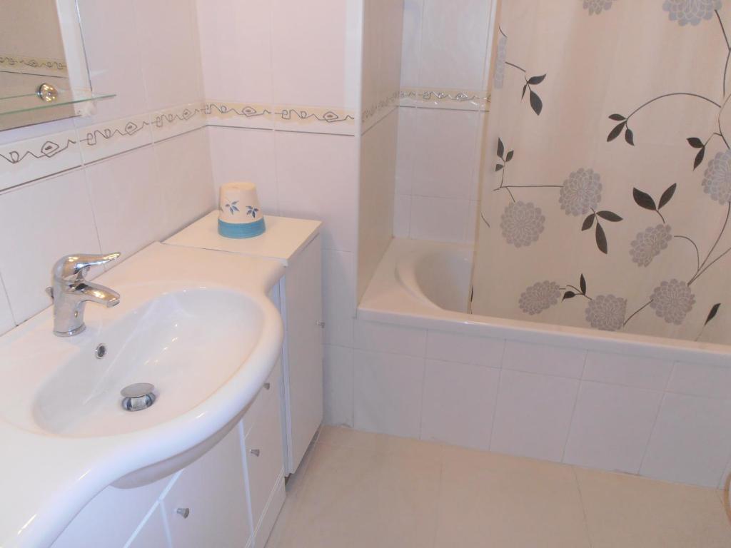 Baño blanco con lavabo y bañera en calmo e simpatico apartamento, en Vila Praia de Âncora