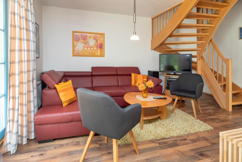ein Wohnzimmer mit einem roten Sofa und einem Tisch in der Unterkunft Ferienpark Freesenbruch Doppelhaushälfte 12 - Sommerlust in Zingst