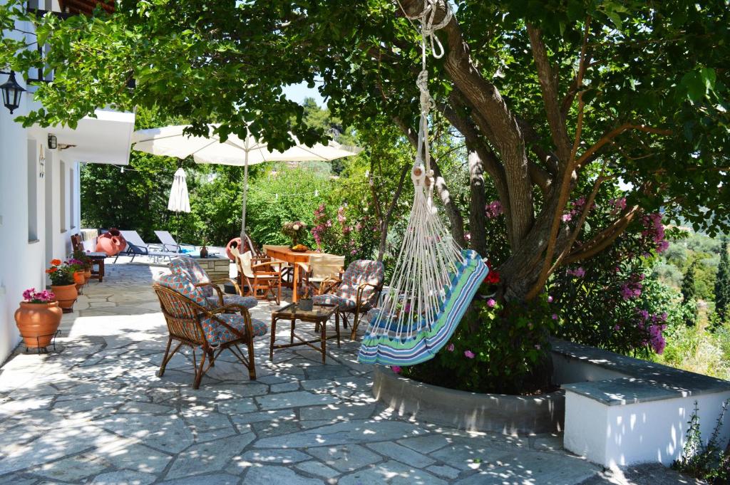 un patio con sillas y una hamaca bajo un árbol en Alikias Country House, en Panormos Skopelos