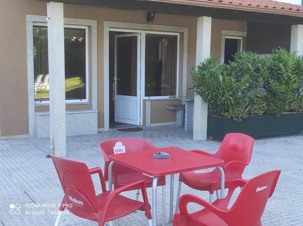 een rode tafel en stoelen voor een huis bij Casa das Pedras in Vieira do Minho