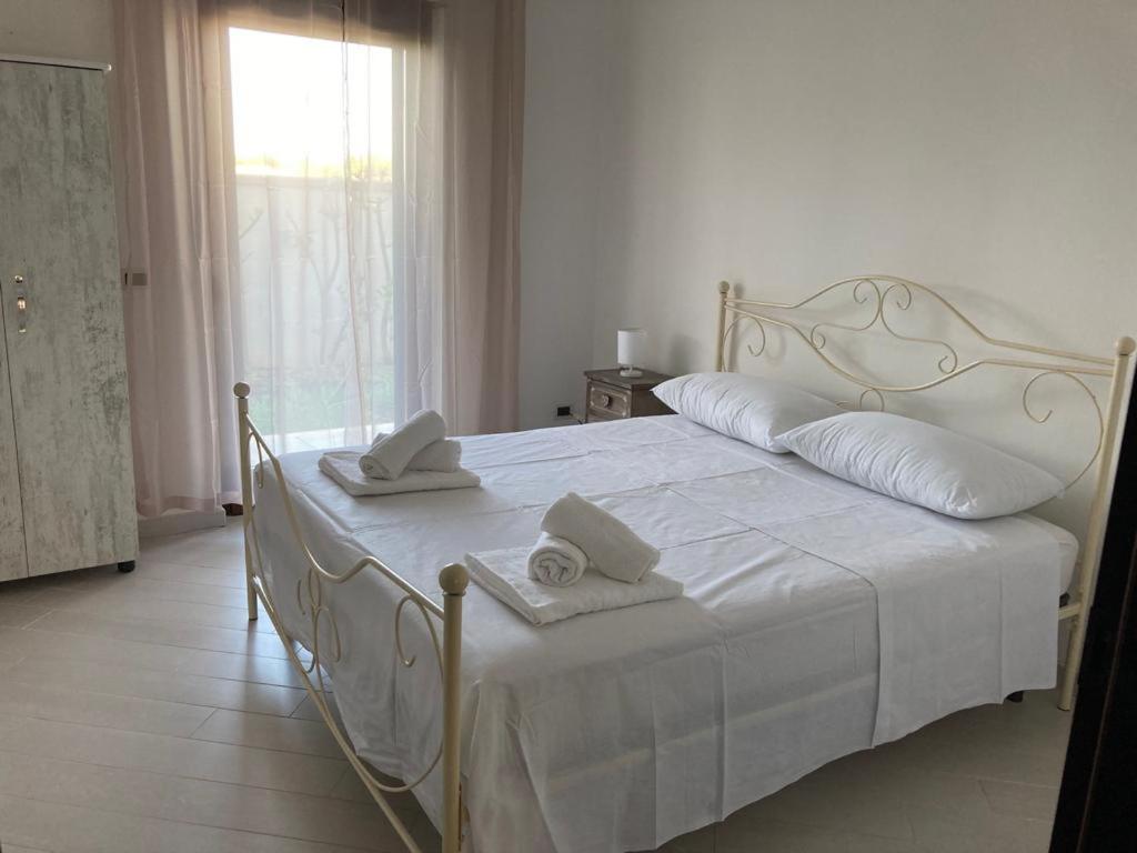 una camera da letto con un letto bianco e asciugamani di Casa Ulivo a Pulsano