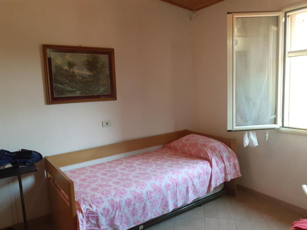 mała sypialnia z łóżkiem i oknem w obiekcie Casa Solanas new w mieście Sìnnai