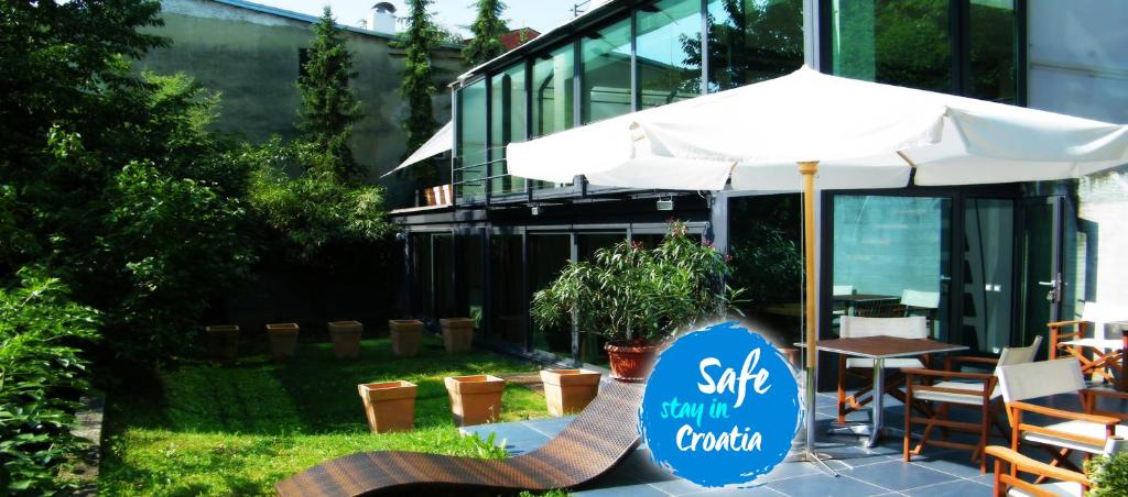 un patio con sombrilla, mesa y sillas en Hotel President en Zagreb