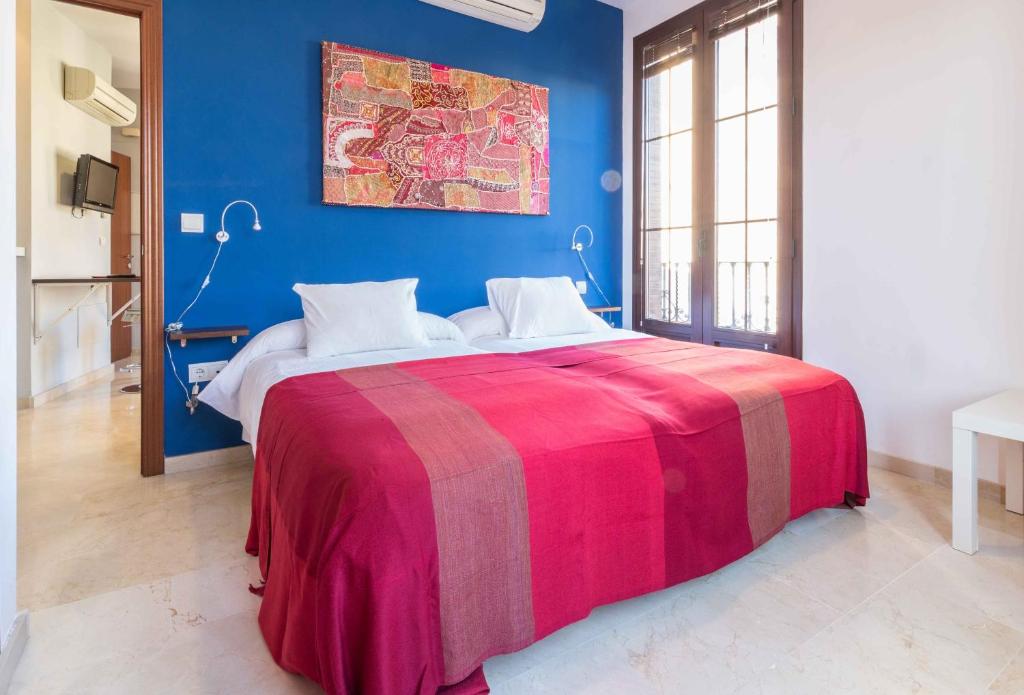 a bedroom with a large bed with a colorful blanket at Rey de Sevilla Flats - Macarena in Seville