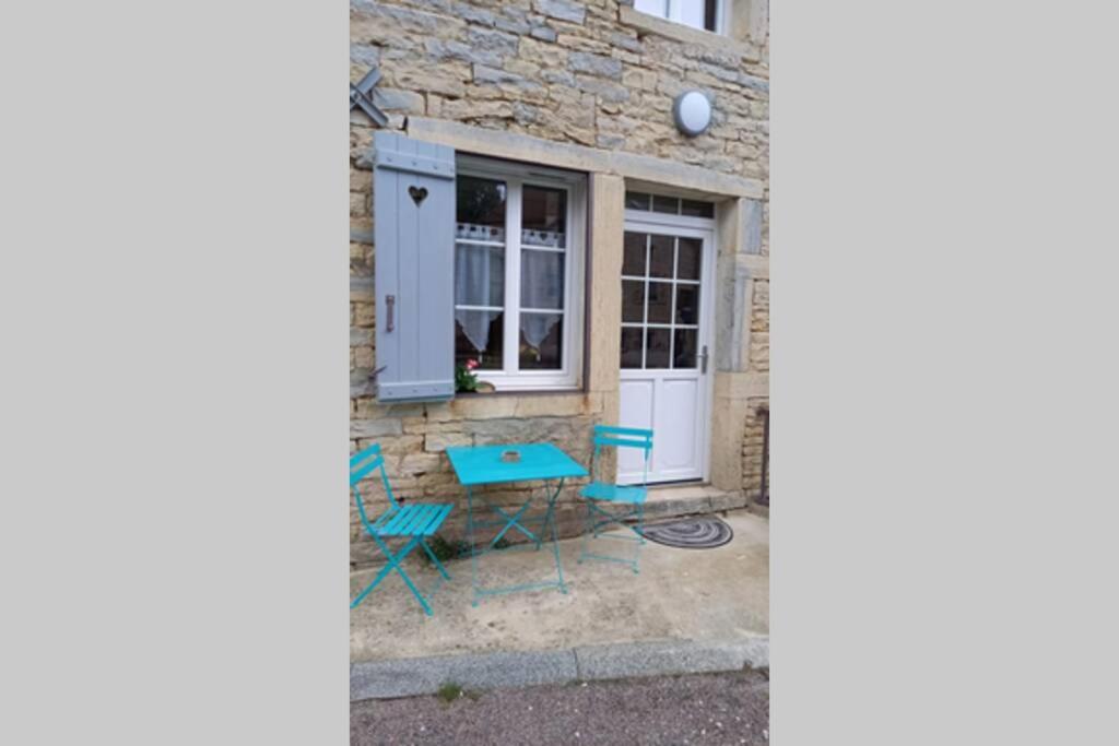 una casa con una mesa azul y sillas frente a una ventana en Petit gîte rural - la Forge - en Sainte-Marie-sur-Ouche
