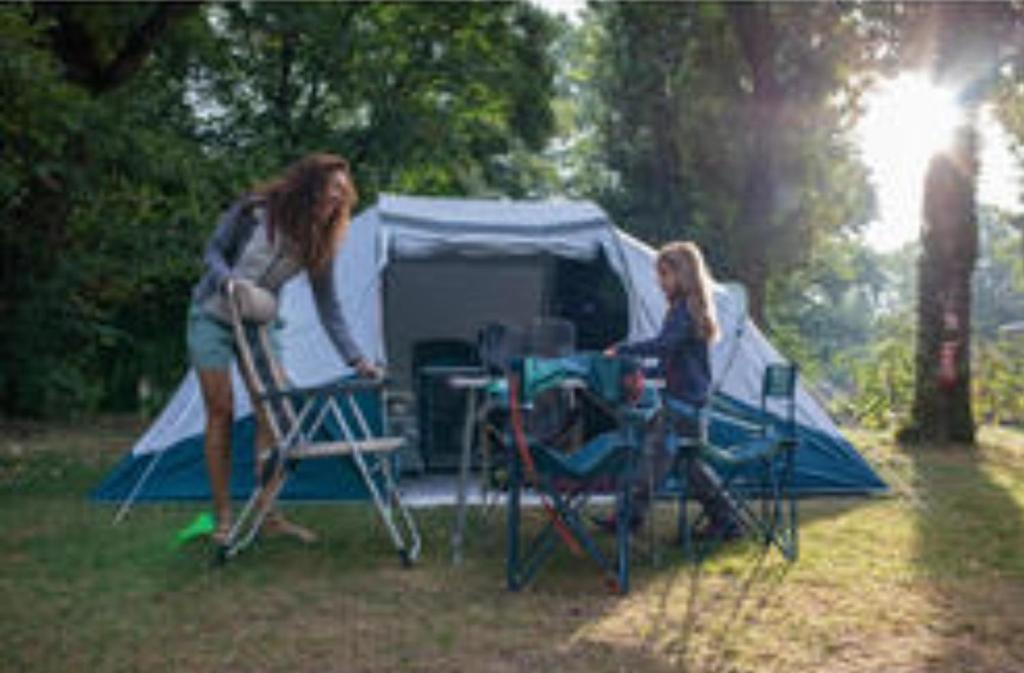 two women standing in front of a tent at Les Hortensias grande tente familiale deux chambres et séjour vue mer sur camping nature in Plestin-les-Grèves