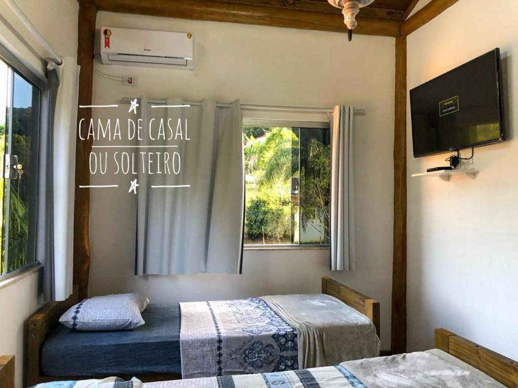 1 dormitorio con 2 camas, ventana y TV en Flat rústico e aconchegante próximo a Paraty e Trindade, en Paraty