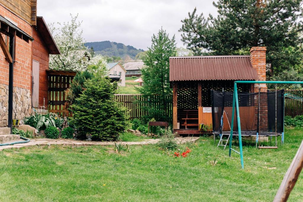 einen Garten mit einem Schlagkäfig und einem Zaun in der Unterkunft Котедж з неймовірними краєвидами in Slawske