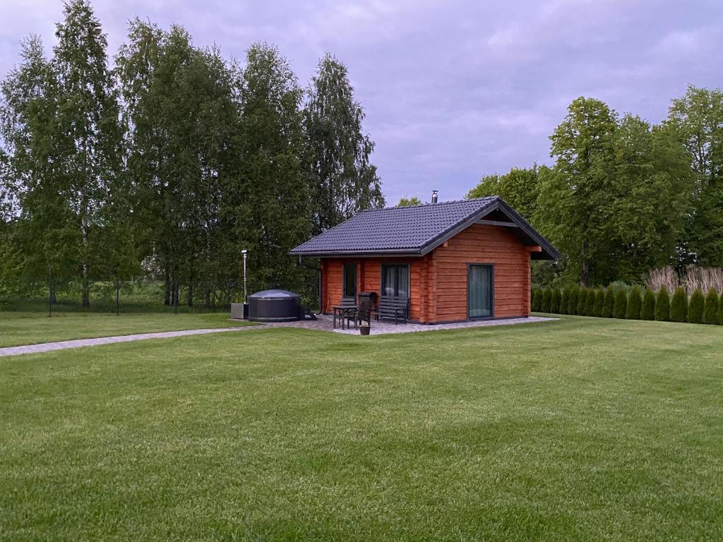 een klein huis met een grill in een tuin bij Dūjas in Duķuri