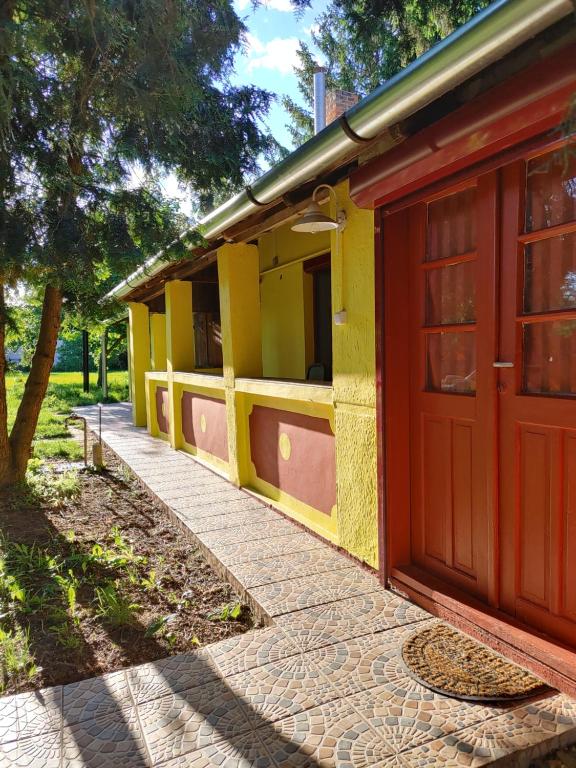 Napsugár Apartman في أبادزالوك: مبنى اصفر واحمر بباب احمر