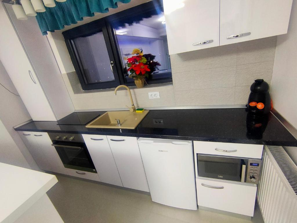 eine Küche mit weißen Schränken, einem Waschbecken und einem Fenster in der Unterkunft Seven Luxury in Mamaia Nord – Năvodari
