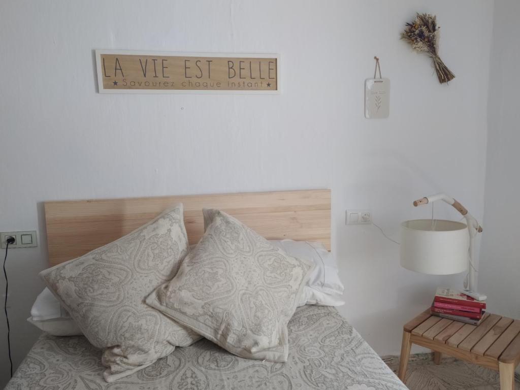 um quarto com uma cama com almofadas e uma placa na parede em La Motilla Barbate em Barbate