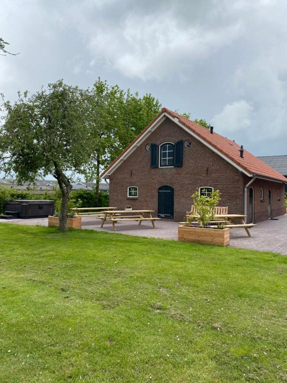 een groot bakstenen gebouw met banken en een boom bij Valleihoeve in Woudenberg