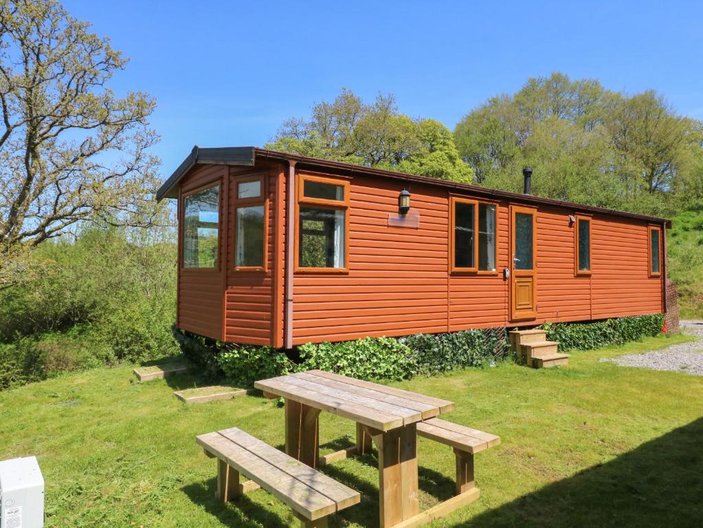 an orange tiny house with a picnic table and a bench at Valley Lodge in Tiverton
