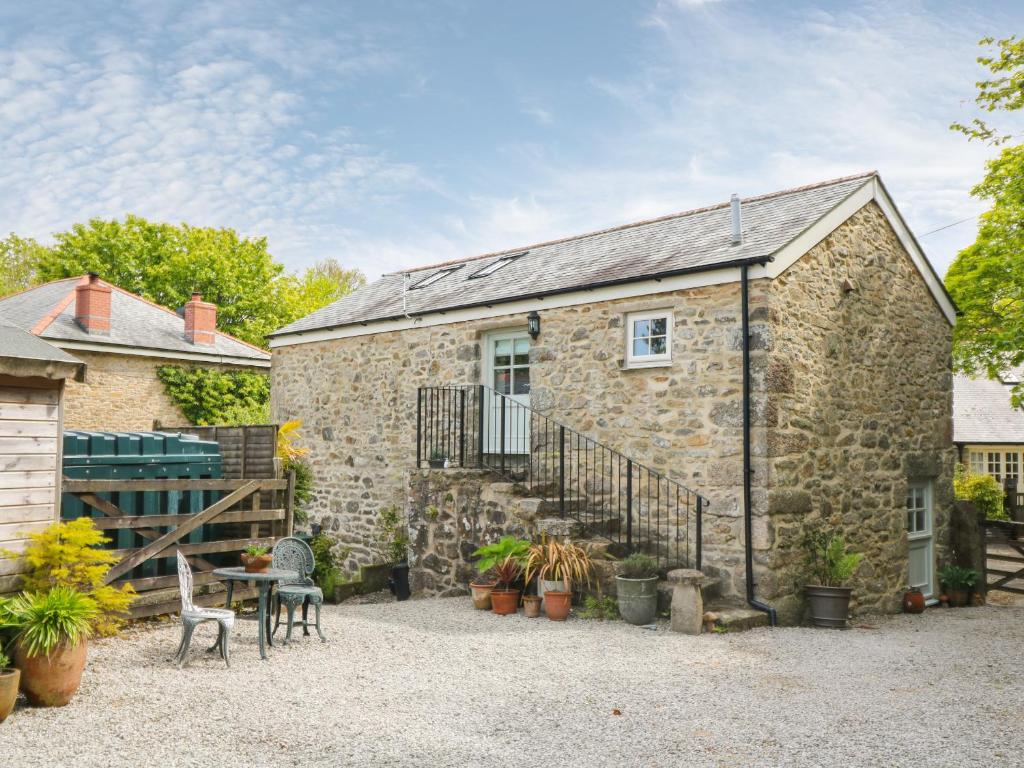 a stone house with a table and chairs in front of it at Trevoole Barn in Camborne