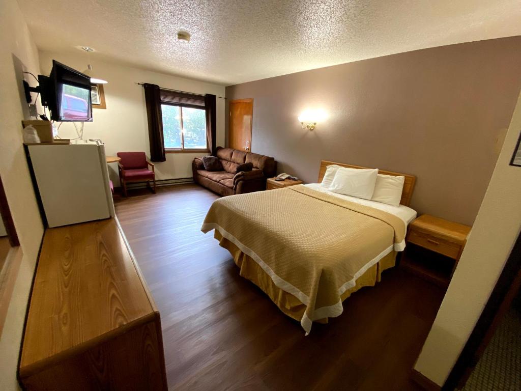 a hotel room with a bed and a couch at Woodland Inn & Suites in Medford