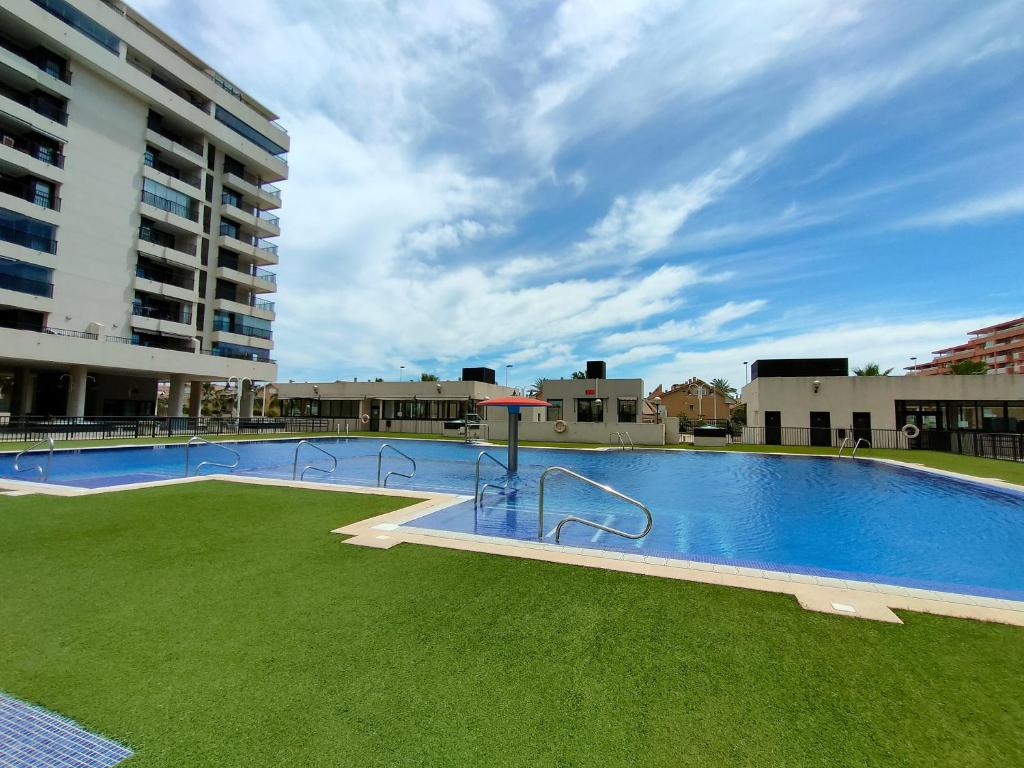 una gran piscina con césped junto a un edificio en NON STRESS First Level, en Valencia